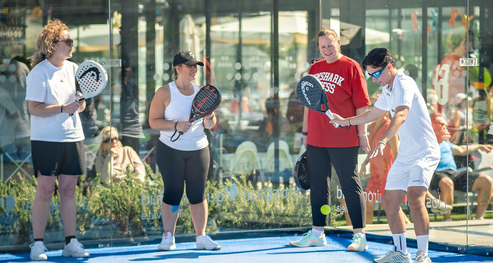 Mensen die uitleg krijgen van een trainer op de padelbaan